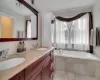 Bathroom featuring vanity, a relaxing tiled tub, and tile patterned floors