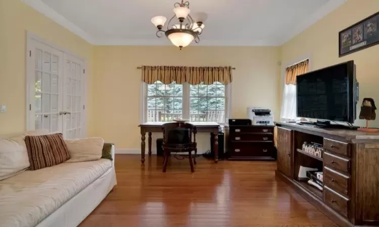 Home office featuring dark hardwood flooring, crown molding, and a chandelier