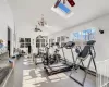 Gym with ceiling fan, lofted ceiling with skylight, and tile patterned flooring