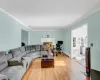 Living room with ornamental molding and light wood-type flooring