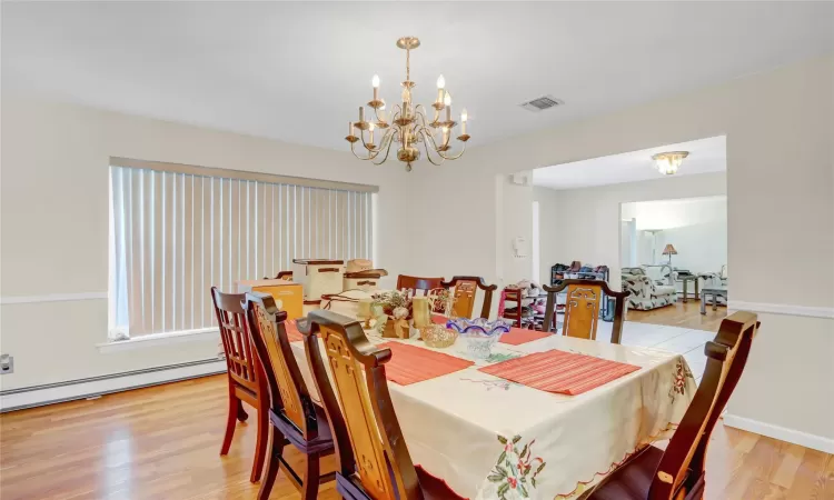 Dining area with a chandelier, light hardwood / wood-style floors, and a baseboard heating unit