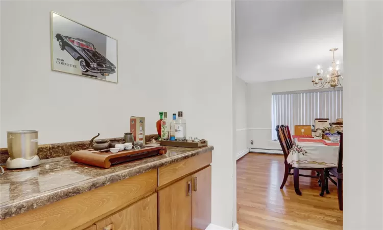 Bar featuring a baseboard heating unit, light hardwood / wood-style floors, and a chandelier