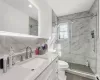 Bathroom featuring backsplash, vanity, walk in shower, a baseboard heating unit, and toilet