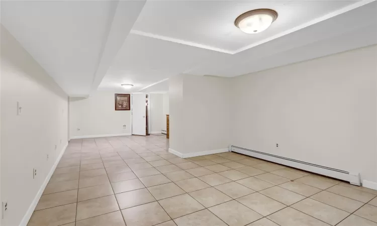 Tiled empty room with a baseboard heating unit