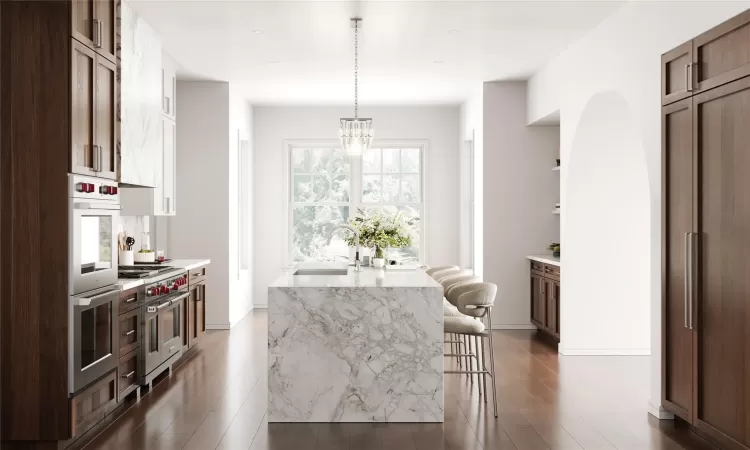 Kitchen with sink, pendant lighting, double oven range, a breakfast bar area, and an island with sink