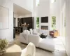 Living room featuring a towering ceiling, a healthy amount of sunlight, and light wood-type flooring