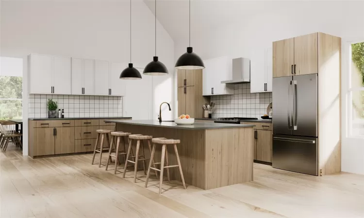 Kitchen with wall chimney exhaust hood, stainless steel fridge, white cabinets, and pendant lighting