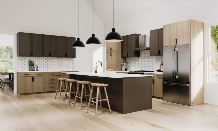 Kitchen with decorative backsplash, wall chimney range hood, a center island with sink, stainless steel refrigerator, and hanging light fixtures