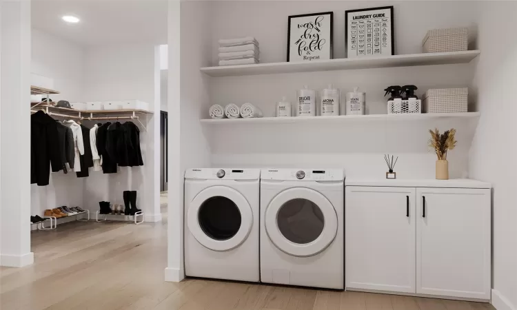 Clothes washing area with cabinets, washing machine and dryer, and light hardwood / wood-style floors