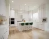 Kitchen featuring a center island, white cabinets, a kitchen breakfast bar, light wood-type flooring, and double oven