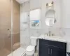 Bathroom featuring tile walls, vanity, a shower with shower door, and toilet