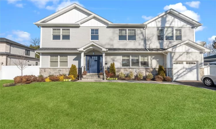 View of front facade featuring a front yard and a garage