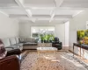 Living room with coffered ceiling, beam ceiling, crown molding, and wood-type flooring