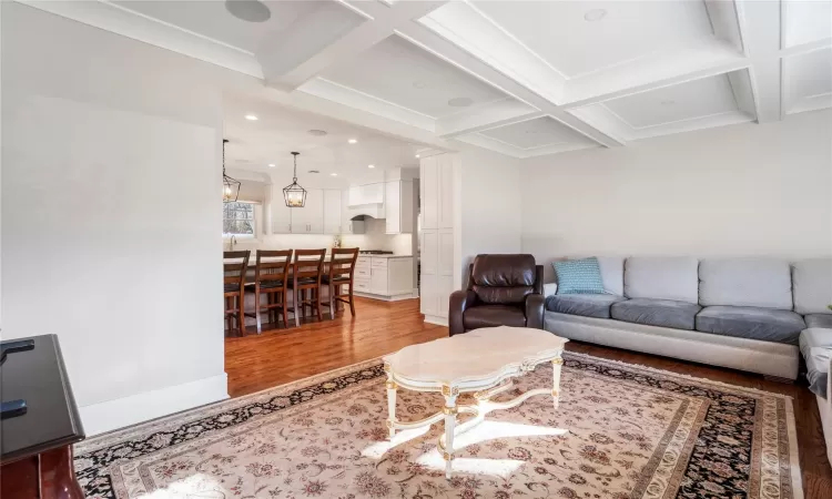 Living room with wood-type flooring, crown molding, coffered ceiling, and beam ceiling