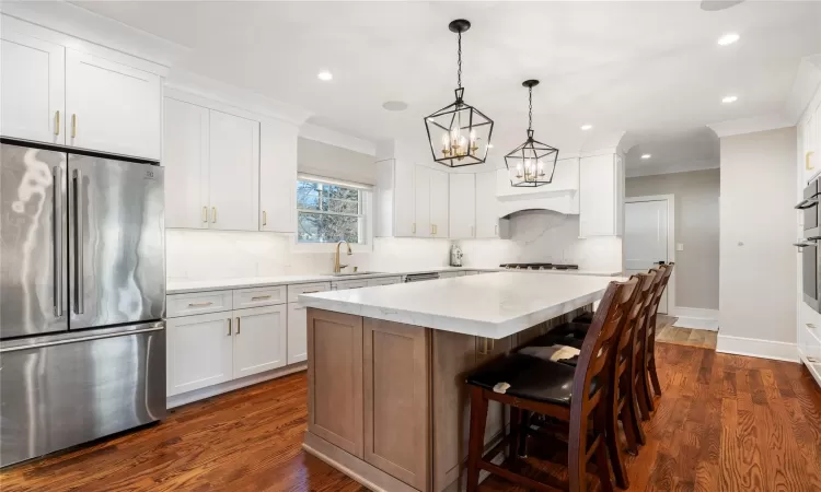 Kitchen featuring a kitchen island, white cabinetry, pendant lighting, and appliances with stainless steel finishes