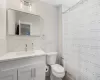 Bathroom featuring tile walls, toilet, and vanity