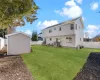 Rear view of house with central air condition unit, a storage unit, and a yard