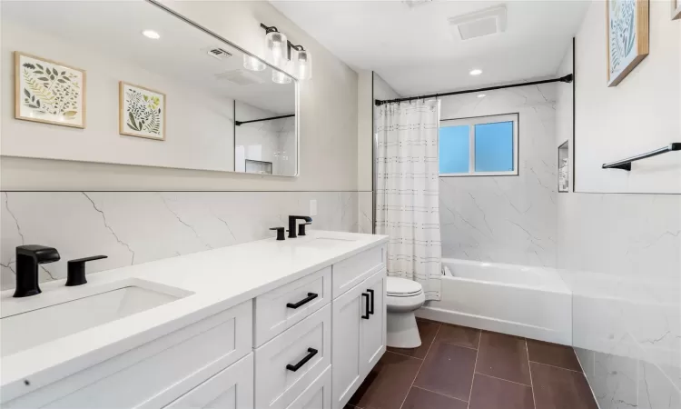 Full bathroom with toilet, shower / tub combo with curtain, and vanity