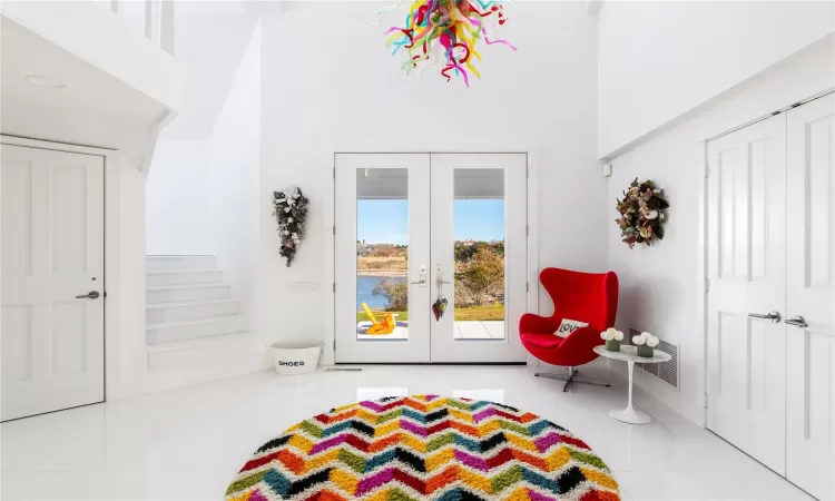 Recreation room featuring french doors, light tile patterned floors, and a high ceiling