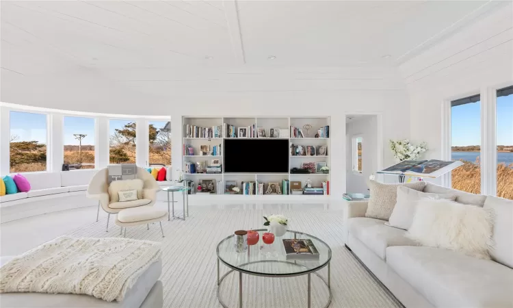 Living room with a towering ceiling, built in features, and wood ceiling