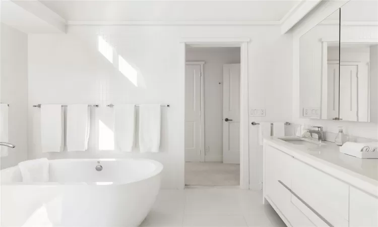 Bathroom featuring tile patterned floors, vanity, and a tub to relax in