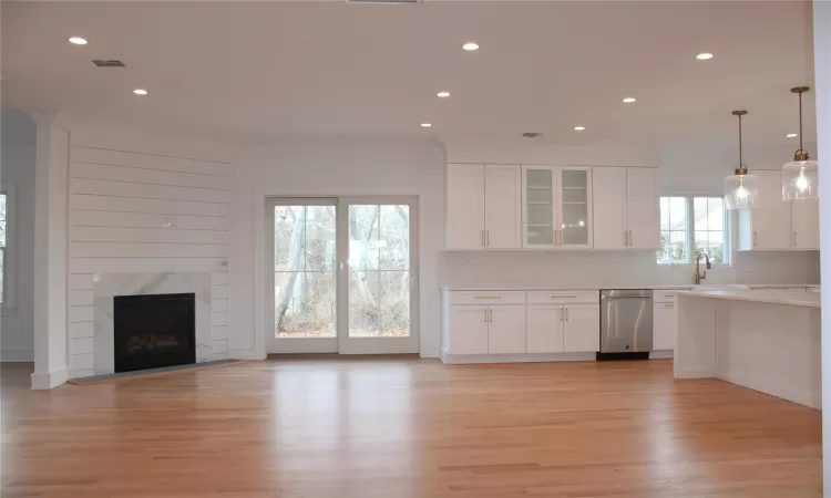 Kitchen featuring stainless steel dishwasher, pendant lighting, white cabinetry, and a wealth of natural light