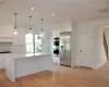 Kitchen with light hardwood / wood-style floors, a center island, white cabinetry, and stainless steel appliances