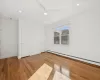 Unfurnished bedroom with hardwood / wood-style flooring, ceiling fan, and a baseboard heating unit