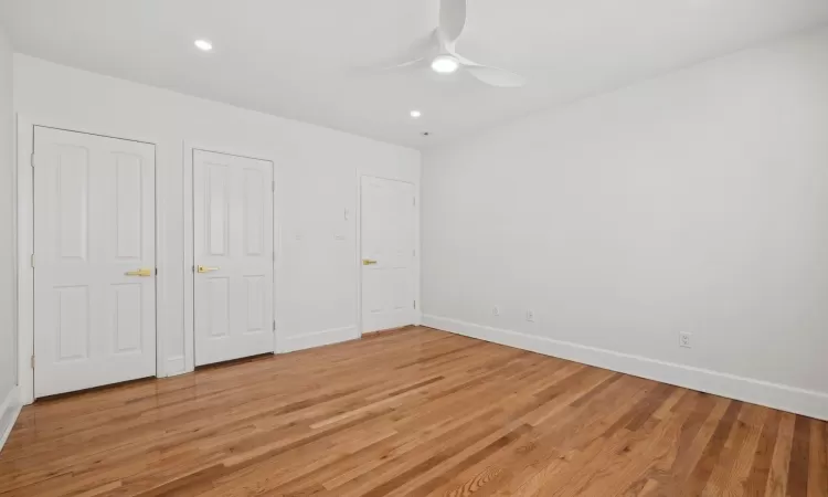 Unfurnished bedroom with light wood-type flooring, ceiling fan, and multiple closets