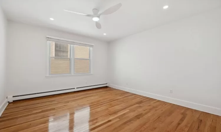 Spare room with ceiling fan, light wood-type flooring, and a baseboard heating unit