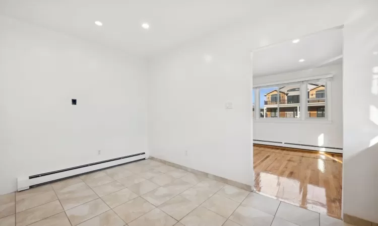 Spare room featuring light tile patterned floors and a baseboard radiator