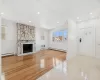 Unfurnished living room featuring a stone fireplace, a wall mounted AC, light tile patterned floors, and a baseboard radiator