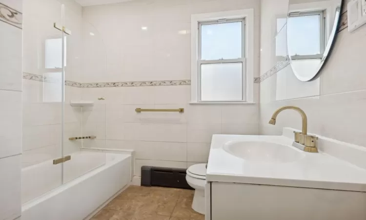 Full bathroom with plenty of natural light, toilet, tile walls, and vanity