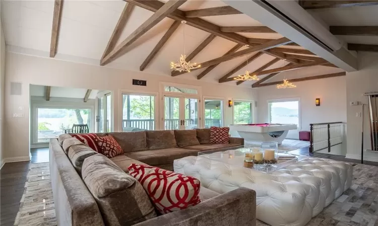 Great room with beamed ceiling, hardwood / wood-style flooring, an inviting chandelier, and a wealth of natural light