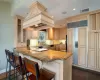 Kitchen with paneled fridge, tasteful backsplash, dark hardwood / wood-style floors, a kitchen bar, and custom range hood