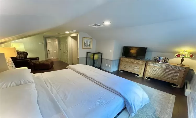 Bedroom with dark hardwood / wood-style floors and vaulted ceiling