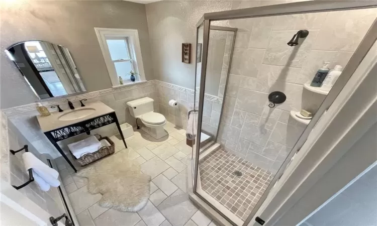 Bathroom with vanity, an enclosed shower, tile walls, and toilet