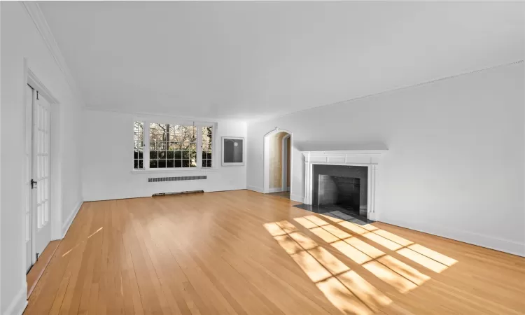 Unfurnished living room with hardwood / wood-style floors and ornamental molding