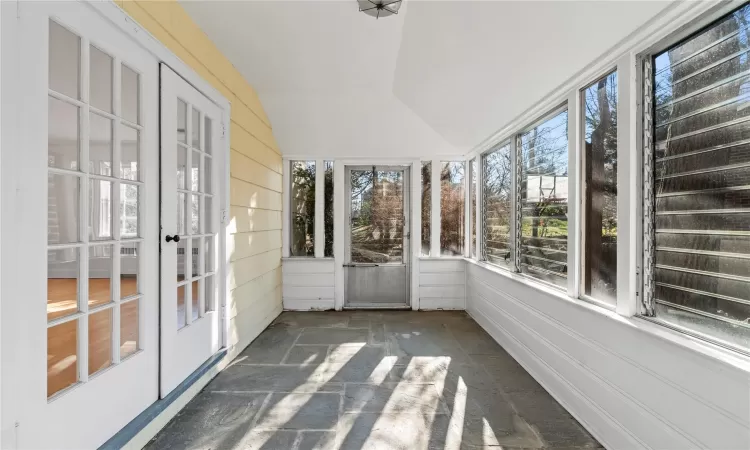 Unfurnished sunroom featuring lofted ceiling