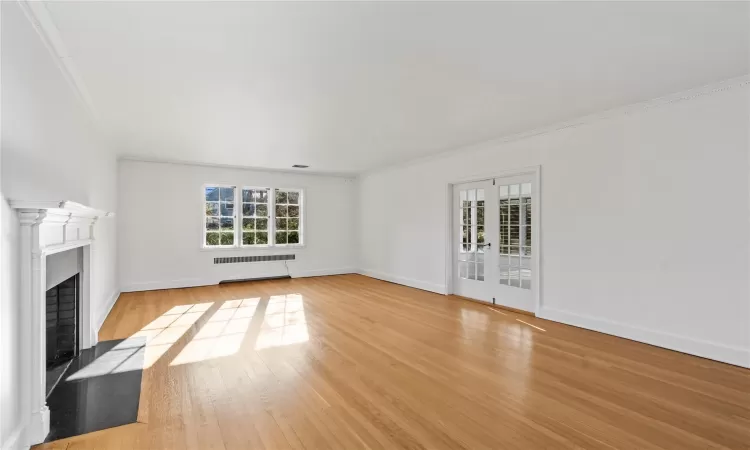 Unfurnished living room featuring light wood-type flooring and ornamental molding