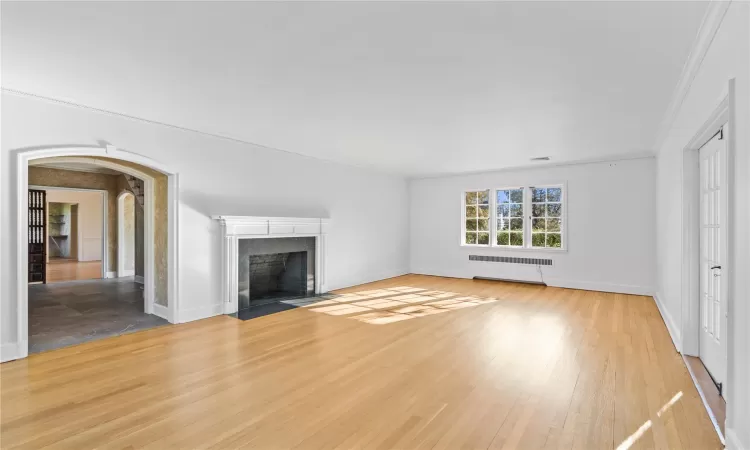 Unfurnished living room featuring wood-type flooring and ornamental molding