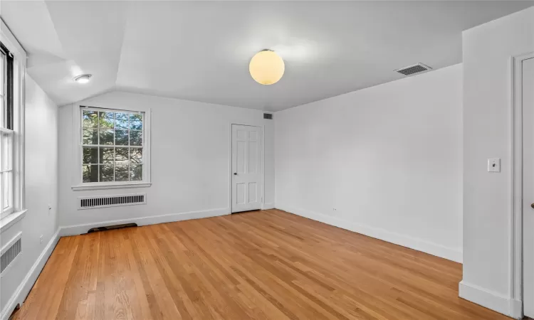 Spare room with light wood-type flooring and vaulted ceiling