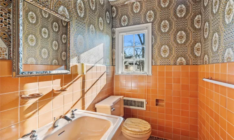 Bathroom featuring toilet, sink, and tile walls