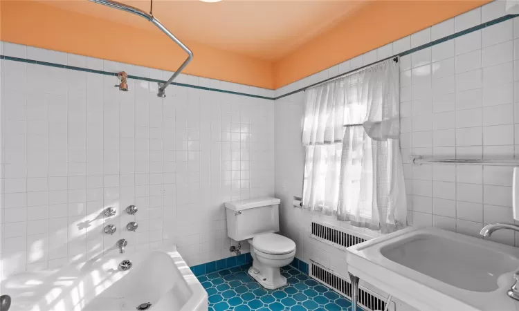 Bathroom featuring sink, tile patterned flooring, toilet, tile walls, and radiator heating unit