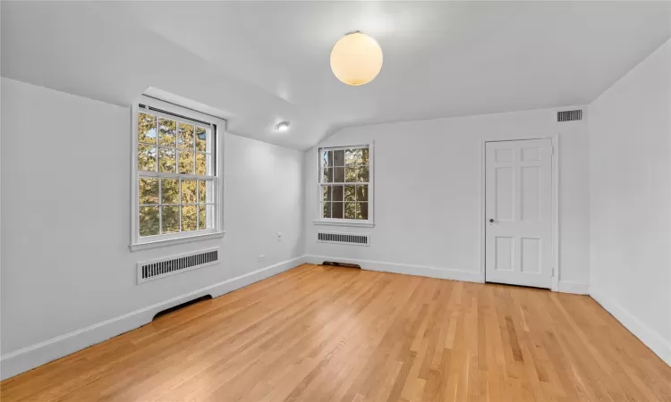 Empty room with lofted ceiling and light wood-type flooring