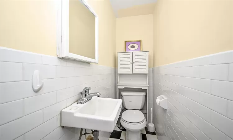 Bathroom with toilet, tile walls, and sink