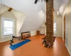 Exercise area featuring wood-type flooring, decorative columns, a wealth of natural light, and lofted ceiling