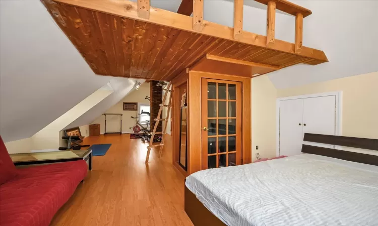 Bedroom featuring light hardwood / wood-style flooring, a closet, lofted ceiling, and wood ceiling