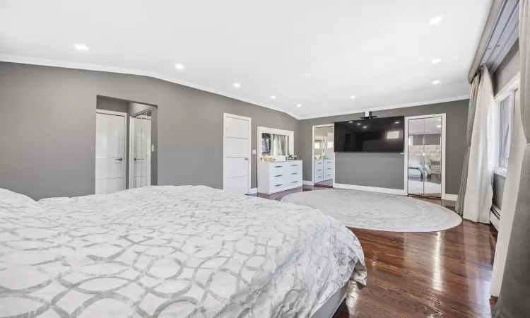 Bedroom featuring hardwood / wood-style floors, vaulted ceiling, and crown molding