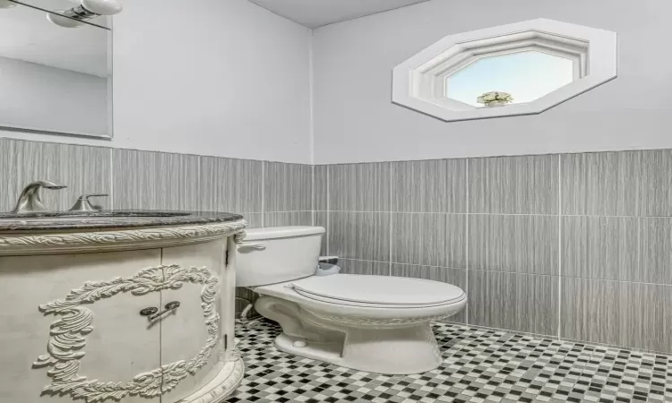 Bathroom featuring tile patterned floors, sink, tile walls, and toilet